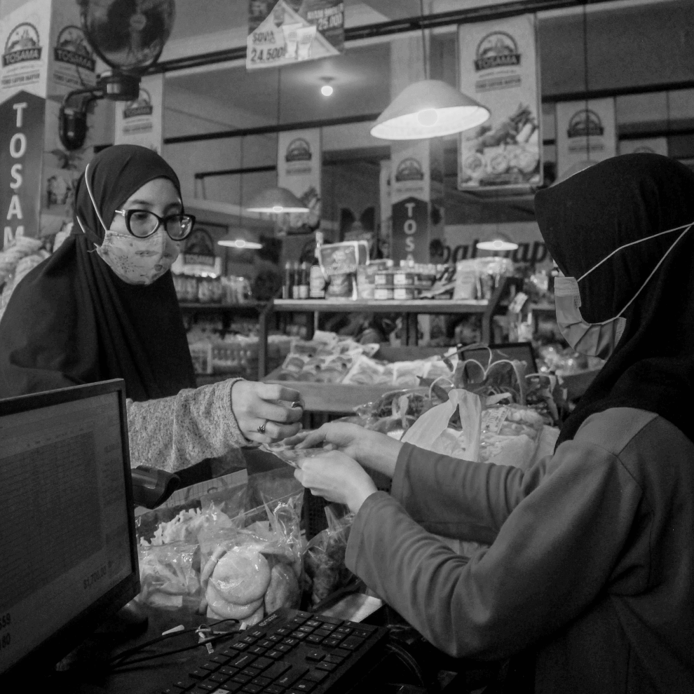 A woman paying another woman at the cash register
