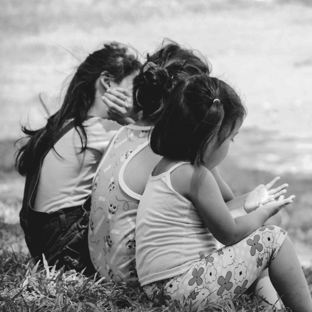 Three children dealing with poverty and hunger sitting on the grass