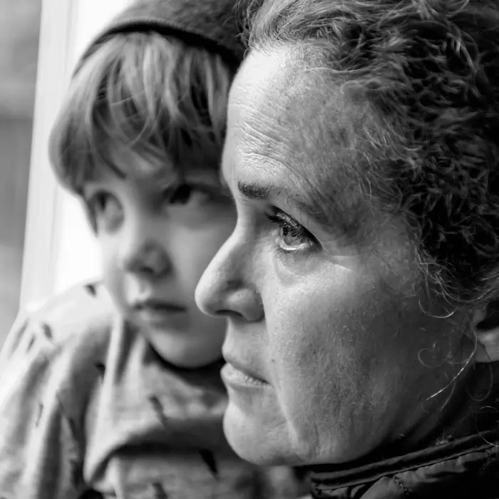 Homeless, impoverished woman holds her child as they look out the window - EPIC